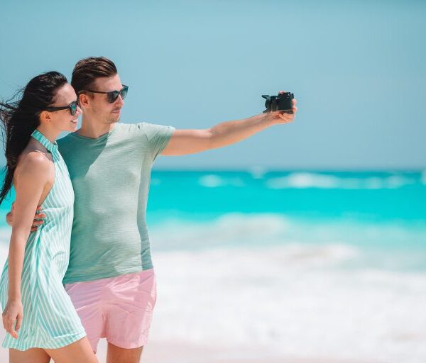 happy-couple-taking-a-photo-on-white-beach-on-hone-2021-08-27-14-37-09-utc-min-768×512